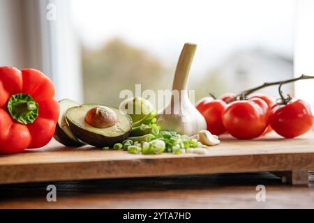 Légumes sains et ingrédients frais sur planche à découper en bois devant la fenêtre lumineuse de la cuisine. Concept nutrion sain pour un régime printanier. Espace pour le texte. Banque D'Images