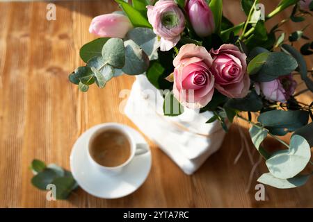 Nature morte avec des roses roses roses et une tasse de café. Fond pour les salutations de fête des mères. Vue de dessus avec faible profondeur de champ et espace pour le texte. Banque D'Images