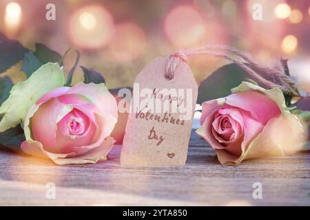 Roses avec une salutation sur une table en bois devant un fond abstrait avec bokeh pour une carte de Saint-Valentin Banque D'Images