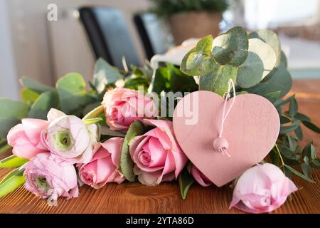 Bouquet de roses roses avec ranoncule et forme de coeur rose sur la table en bois pour les salutations de fête des mères. Banque D'Images