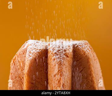 Avec Pandoro saupoudrage de sucre glace sur fond orange Banque D'Images