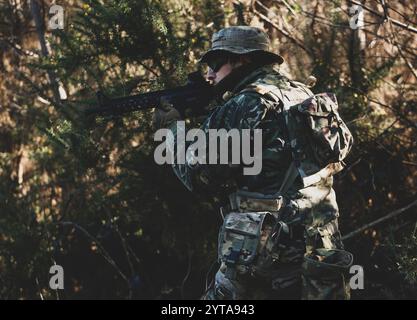 Joueur de jeu militaire Airsoft en uniforme de camouflage avec fusil d'assaut armé Banque D'Images