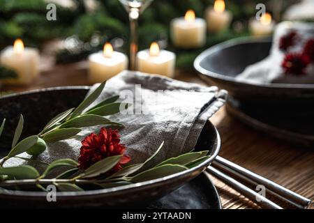 Cadre de fête avec branche d'olivier et bougie sur une table décorée de noël. Fond de style de vie pour la gastronomie festive avec une courte profondeur de champ. Banque D'Images