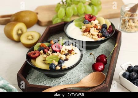 Petit déjeuner sain, bol de yaourt grec avec divers fruits et céréales. Kiwi doré, cerise, myrtille et raisins verts Banque D'Images