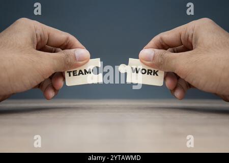 Deux mains tenant des pièces de puzzle avec les mots «ÉQUIPE» et «TRAVAIL». Concept de travail d'équipe et de collaboration. Banque D'Images