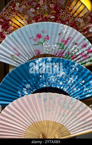 Un motif de multiples fans japonais pliants colorés, ou «sensu» vu dans une vitrine de magasin à Arashiyama, Kyoto, Japon. Banque D'Images