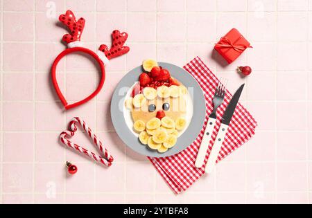 Assiette avec crêpe en forme de Père Noël sur fond de tuile rose Banque D'Images