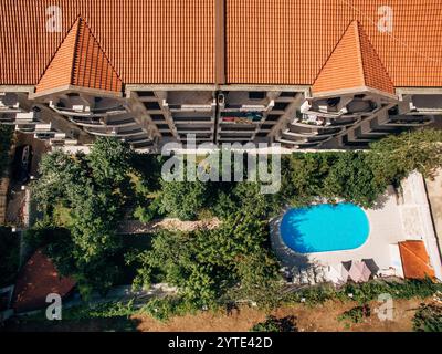 Piscine ovale avec chaises longues parmi les arbres verts dans la cour d'un immeuble. Vue de dessus Banque D'Images