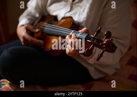 Gros plan des mains d'un musicien jouant habilement du violon, capturant l'essence de la musique et de l'art dans un cadre chaleureux et intime. Banque D'Images