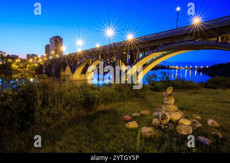 Un pont sur une rivière avec des lumières qui brillent dessus. Le pont est éclairé la nuit, créant une atmosphère paisible et sereine Banque D'Images