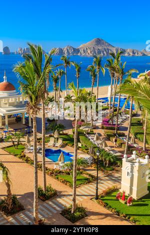 Une belle plage avec des palmiers et une piscine. La piscine est entourée de parasols et de chaises Banque D'Images