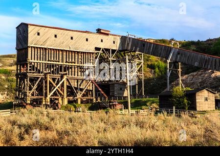 Un grand bâtiment ancien avec un toit en bois et une clôture en bois. Le bâtiment est entouré d'un champ d'herbe Banque D'Images