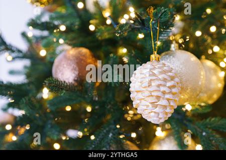 Arbre de Noël décoré avec des ornements festifs dorés sur fond de guirlande de lumières brillantes. Ambiance festive dans un espace intérieur confortable, parfait pour wi Banque D'Images