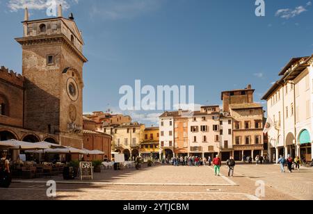 Mantoue, Italie - 15 septembre 2024 : la tour de l'horloge sur la Piazza delle Erbe avec des palais historiques et l'église Banque D'Images