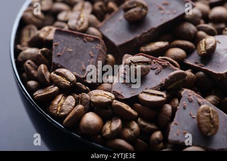 Chocolat noir maison cassé et grains de café dans un bol noir. Low Key. Gros plan. Banque D'Images