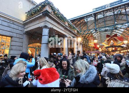 Londres, Royaume-Uni 7 décembre 2024. Les acheteurs de Noël étaient ravis de voir la neige tomber sur la place de Covent Garden. À travers la période festive, la neige artificielle tombera toutes les heures, ajoutant à l'atmosphère amusante. Crédit : Monica Wells/Alamy Live News Banque D'Images