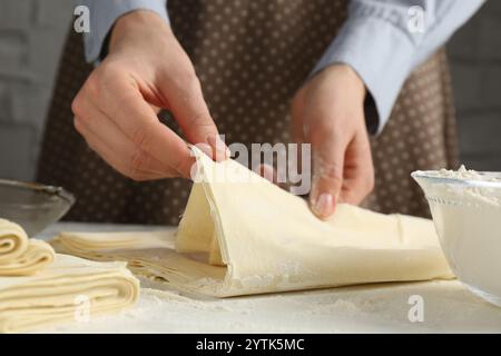 Femme faisant de la pâte feuilletée à la table blanche, gros plan Banque D'Images