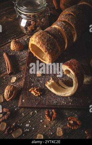 Pain sucré hongrois, tranché sur une planche de bois, saupoudré de sucre et de noix, de bâtonnets de cannelle et de bonbons de roche Banque D'Images