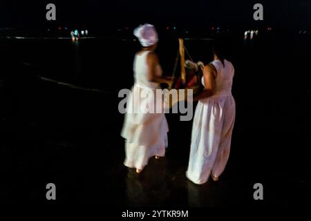 Les dévots de l'Umbanda, la tradition religieuse afro-uruguayenne, portent un bateau de papier lors d'une cérémonie rituelle en l'honneur de la déesse Yemanjá sur le bord de la mer à Montevideo, en Uruguay. Banque D'Images