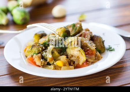 Choux de Bruxelles cuits avec des légumes et des épices, sur une table en bois. Banque D'Images