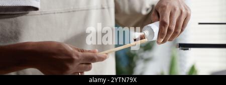 Website header shot de l'homme afro-américain appliquant du dentifrice sur une brosse à dents en bambou prenant soin de l'hygiène dentaire dans la salle de bain, espace de copie Banque D'Images