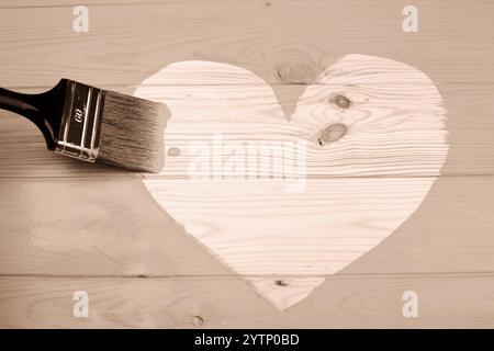 Forme de coeur peinte sur une surface en bois avec un grand pinceau, symbolisant la créativité Banque D'Images