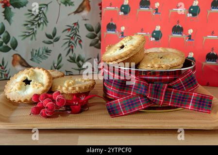 Tartes hachées en étain décorées avec un ruban tartan avec noeud et lâche sur un plateau avec des baies. Banque D'Images