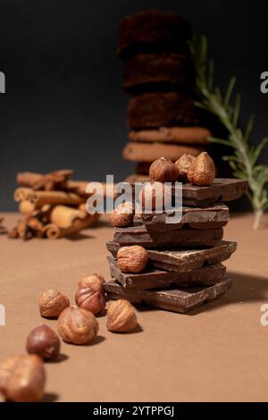 Morceaux de chocolat avec des noisettes sur fond brun de biscuits et d'épices. Idées culinaires créatives Banque D'Images