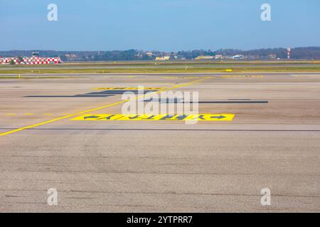 Piste avec des lignes jaunes proéminentes marquant le bord. Panneaux de signalisation routière pour le guidage sur la piste de l'aéroport. Lignes peintes sur le sol indiquant les directions fo Banque D'Images