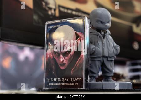 Krasnogorsk, Russie. 28 novembre 2024. Une figurine d'action en 3D du personnage principal du jeu 'The Hungry Town' et une cassette audio avec la bande originale du jeu vue sur le stand des développeurs pendant l'exposition. RED Expo est la plus grande exposition internationale de divertissement interactif en Russie. Du 28 novembre au 1er décembre 2024, il rassemble des créateurs et distributeurs de jeux vidéo, des producteurs de contenus connexes, des cosplayers, des fans de jeux et d’autres acteurs de l’industrie du jeu au complexe d’exposition Crocus Expo. Crédit : SOPA images Limited/Alamy Live News Banque D'Images