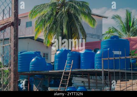 Assortiment de grands réservoirs d'eau en plastique bleus sur un présentoir. Réservoirs cylindriques utilisés pour stocker de l'eau ou d'autres liquides à vendre. Banque D'Images