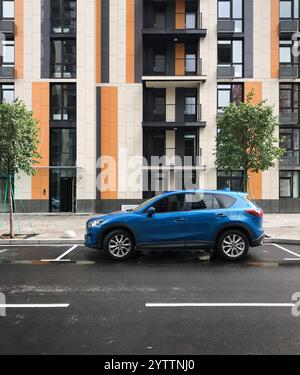 Voiture bleue garée sur une rue en face d'un immeuble résidentiel moderne. Vue de profil latérale du multisegment Mazda CX-5 en milieu urbain. Banque D'Images