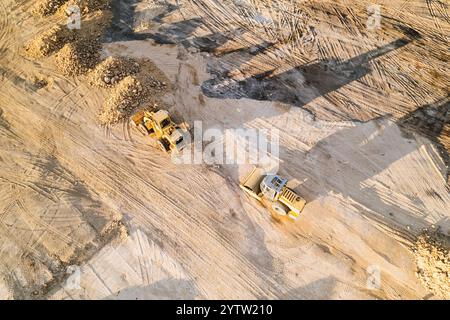 Drone zénithal vue. Machinerie lourde au travail pendant un projet de construction, déplacement de terre et façonnage du paysage sur le chantier de construction Banque D'Images