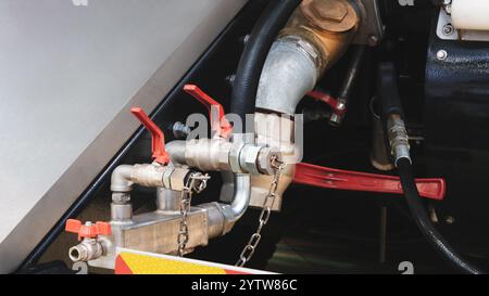 Une chaîne est attachée à un tuyau. La chaîne est attachée à une poignée rouge Banque D'Images