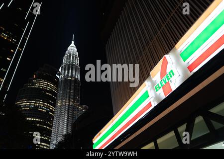 KUALA LUMPUR, MALAISIE - 08 NOVEMBRE 2023 : magasin 7-Eleven avec les tours Petronas en arrière-plan. 7-Eleven est une chaîne mondiale de magasins de proximité de Banque D'Images