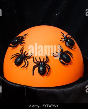 Décor d'Halloween - beaucoup d'araignées noires sur une veilleuse orange. Sur un fond noir, placez-le pour le texte. Banque D'Images