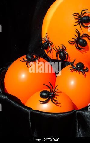 Décor d'Halloween - beaucoup d'araignées noires sur une veilleuse orange. Sur un fond noir, placez-le pour le texte. Banque D'Images