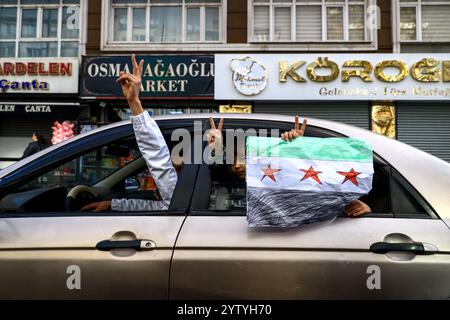 Istanbul, Turquie. 08 décembre 2024. Un enfant agite le drapeau syrien de l'intérieur d'une voiture dans les rues d'Istanbul pour célébrer l'annonce de la chute du régime d'Assad. Crédit : SOPA images Limited/Alamy Live News Banque D'Images