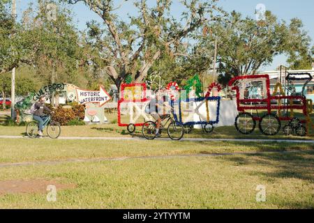 Usage éditorial uniquement le 7 décembre 2024. Gulfport, Floride, États-Unis. Décoration des vacances de Noël deux personnes sur des vélos et flèche de panneau de direction dans Clymer Park tard Banque D'Images