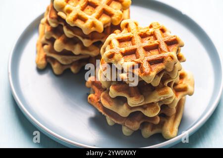 Deux piles de gaufres belges ou viennoises fraîchement cuites sur une assiette bleue. Photo de haute qualité Banque D'Images