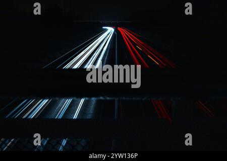 Traînées de lumière rouge et blanche provenant de voitures sur une autoroute capturées à l'aide de photographies à exposition longue. Infrastructure urbaine et mouvement nocturne. Banque D'Images