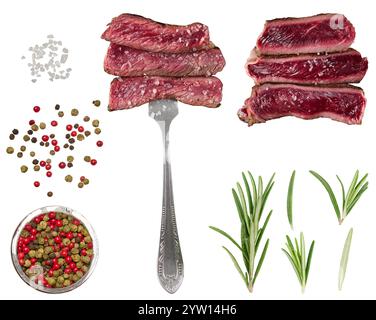 Des tranches de bœuf juteuses, saupoudrées de gros sel, sont brochées sur une fourchette. Un mélange de grains de poivre noir, rouge, vert multicolore, brins de ro frais Banque D'Images