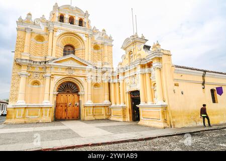 Façade extérieure de l'église Iglesia Santo Hermano Pedro de San José Betancur ou église des apôtres San Pedro, une église catholique ornée construite dans le style baroque en 1654 à Antigua, Guatemala. L'église jaune vif est entièrement restaurée et offre un hôpital de charité pour les pauvres. Banque D'Images