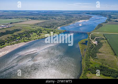 Une rivière avec un pont au-dessus et quelques arbres en arrière-plan. Le ciel est clair et l'eau calme Banque D'Images