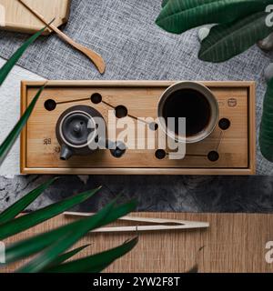 Une installation de thé magnifiquement sereine et apaisante présente une théière élégante et une tasse, exposées sur un plateau en bambou Banque D'Images