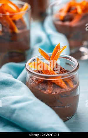 Moka souris ou mousse au chocolat avec zeste d'orange confite et pétales d'amande dans des verres en verre sur un fond bleu avec une serviette bleu ciel. Photo de haute qualité Banque D'Images