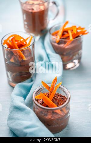 Moka souris ou mousse au chocolat avec zeste d'orange confite et pétales d'amande dans des verres en verre sur un fond bleu avec une serviette bleu ciel. Photo de haute qualité Banque D'Images