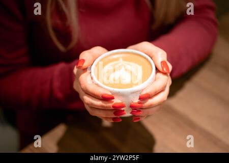 femme tenant une tasse de café avec de l'art latte Banque D'Images
