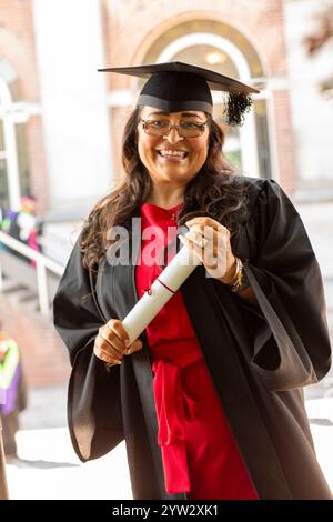 Femme souriante en tenue de graduation titulaire d'un diplôme, Bournemouth, Dorset UK Banque D'Images