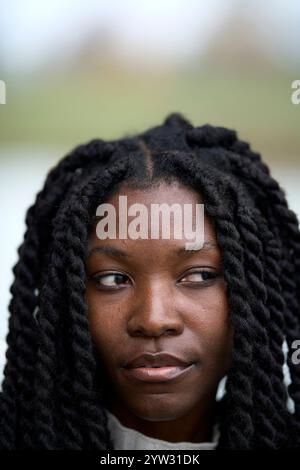 Gros plan d'une jeune femme réfléchie avec des cheveux tressés regardant loin, Brandebourg, Allemagne Banque D'Images